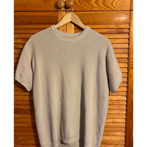 Beige ribbad t-shirt från Zara - Säljer en stilren beige t-shirt med ribbad struktur. Den har korta ärmar och en rund halsringning, perfekt för en avslappnad look.