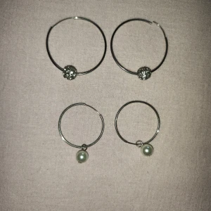 Två par silverörhängen med pärlor och glittriga detaljer - Säljer två par eleganta silverörhängen. Ett par har glittriga kulor och det andra har hängande pärlor. Perfekta för att ge en stilren touch till din outfit. Inte äkta.