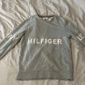 Grå sweatshirt från Tommy Hilfiger - Säljer en stilren grå sweatshirt från Tommy Hilfiger, den är i bra skick då den är var för stor så den har knappt används.