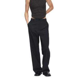 Svarta kostymbyxor, HOPE Wind Trouser - Eleganta svarta kostymbyxor med en klassisk rak passform. Byxorna har midwaist och är utrustade med knappar och dragkedja framtill. Perfekta för en stilren look. HOPE WIND TROUSER. Använda 1 gång