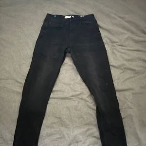 Svarta jeansbyxor från FSBN - Snygga svarta jeansbyxor från FSBN med en tight passform. De har en klassisk design med fem fickor och knappgylf. Perfekta för en stilren look.