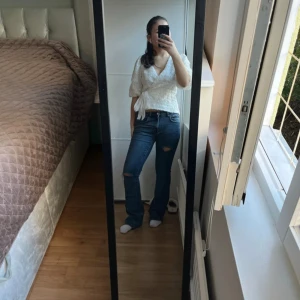 Blå bootcut jeans med hål - Snygga blå bootcut jeans med en klassisk look. De har en medel midja och en liten reva på ena benet för en trendig touch. Perfekta för en avslappnad stil.