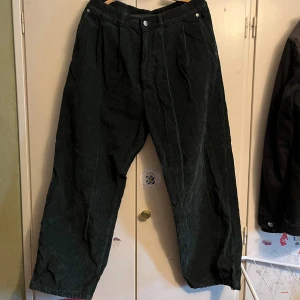 Mörkgröna manchesterbyxor - Snygga mörkgröna manchesterbyxor från Chantuque med elastisk snörning vid bensluten. Byxorna har en avslappnad passform och är perfekta för en stilren look. Köpta second hand men har själv använt fåtal gånger, det finns lite slitage på låren. Midjemått tvärs över är ca 42 cm