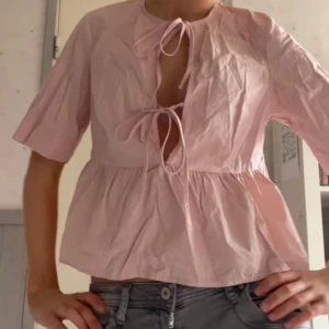 Rosa blus med knytband - Söt rosa blus med knytband framtill och trekvartsärmar. Perfekt för en avslappnad och stilren look💕 Blusen har en luftig passform och är tillverkad i ett lätt material.🩷 skriv vid frågor/intresse (liten slitning kan skicka bild privat)