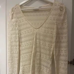 Vit spetsblus från Vila - Säljer en elegant vit spetsblus från Vila i storlek XS. Blusen har en v-ringad design och långa ärmar, perfekt för en stilren look. Den är tillverkad i ett vackert spetsmaterial som ger en romantisk känsla.