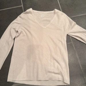 Beige kashmirtröja från Majestic Filatures - Säljer en lyxig beige kashmirtröja från Majestic Filatures. Tröjan har en v-ringad design och långa ärmar, perfekt för en stilren look. Den är tillverkad i 100% kashmir vilket gör den supermjuk och bekväm. Passar perfekt för kyligare dagar.