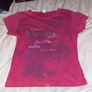 Rosa t-shirt med tryck från Catadel - Säljer en rosa t-shirt från Catadel med tryck av text och mönster på framsidan. T-shirten har korta ärmar och en rund halsringning. Perfekt för en avslappnad stil.