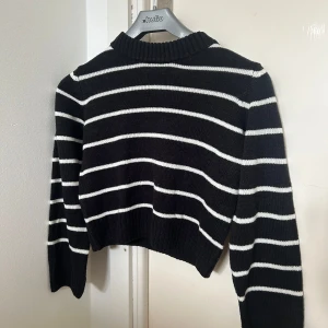 Svart och vit randig tröja från H&M - Prutbart pris! Säljer en svart och vit randig tröja från H&M. Tröjan är stickad och har en croppad passform med långa ärmar. Perfekt för en stilren look. 🖤🤍
