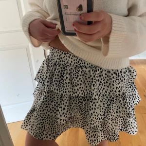 Svartvit leopardmönstrad kjol - Säljer en söt svartvit leopardmönstrad kortkjol med volanger. Kjolen är köpt i en butik på Marstrand. Har en liten fläck som säkert går bort i tvätten, utöver det toppen skick! 