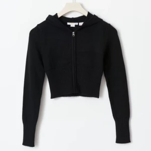 Svart croppad hoodie med dragkedja - Snygg svart croppad hoodie med dragkedja framtill.  Den har långa ärmar och en bekväm huva. 