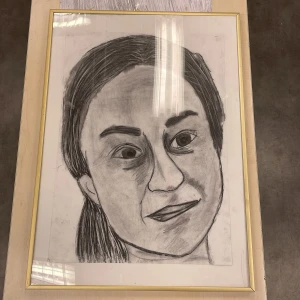 Inramad teckning av ett ansikte i kol - Säljer en inramad teckning av ett ansikte, ritad i kol. Teckningen är inramad med en tunn guldfärgad ram och skyddad av glas. Perfekt för att ge en konstnärlig touch till ditt hem.