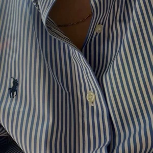 Ralph Lauren skjorta - Snygg blå och vit randig skjorta från Ralph Lauren i storlek M men sitter mer som en S/M. Skjortan är i mycket bra skick och passar perfekt till sommaren, både för killar och tjejer. Vid frågor är det bara att höra av sig💛