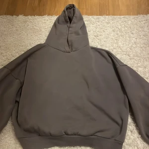Grå hoodie från NLY Trend - Säljer en stilren grå hoodie från NLY Trend i storlek XS. Den har en klassisk design med huva och ribbade muddar vid ärmslut och nederkant. Perfekt för en avslappnad look.