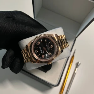 Seiko Mod Klocka - Säljer en elegant handbyggd klocka i roséguld med svart urtavla och romerska siffror. Klockan har en presidental länkarmband och en detaljerad baksida som visar urverket. Perfekt för den som vill ha en stilren och exklusiv accessoar. Specifikationer ⤵️.                                                Diameter: 40mm Movement: Seiko NH35 automatic Thickness: 12.8 mm Glass: Sapphire, anti-scratch Case: 316L stainless steel Bracelet: Presidental 316L stainless steel Crown: Screw Water resistance: 5ATM