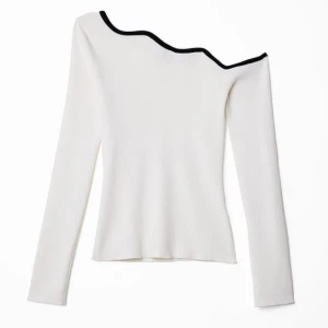 Finstickad tight topp med vågiga axlar - Snygg vit offshoulder topp med svart kantdetalj. Perfekt för en stilren look med en unik asymmetrisk design. Långärmad och tillverkad i ett mjukt material som ger en bekväm passform.