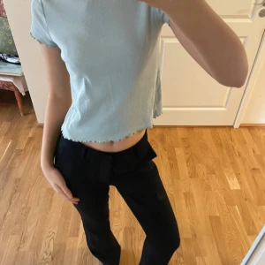 Ljusblå ribbad topp - Säljer en ljusblå ribbad topp med korta ärmar och en croppad design. Perfekt för en avslappnad stil. Toppen har en enkel och stilren look.