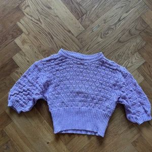 Rosa stickad tröja - Rosa stickad tröja med ett fint mönster. Tröjan har korta ärmar och en ribbad nederkant. Croppad passform.