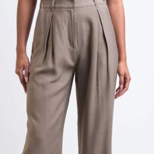 Beige kostymbyxor - Snygga beige kostymbyxor med hög midja och vida ben. Byxorna har veck framtill som ger en elegant touch. Perfekta för en stilren look.