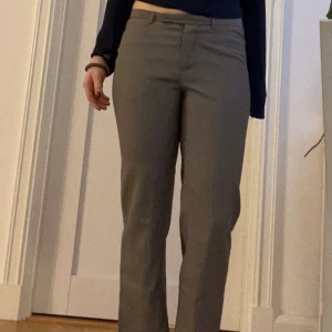 Grå kostymbyxor - Snygga grå kostymbyxor med mellanhög midja och rak passform. Dem är för långa för mig i benen och har därför inte använt så mycket men min mamma gjorde det mer än mig. Det är tunna byxor. Inga defekter och det finns djupa fickor på framsidan. Skriv om du har fler frågor!