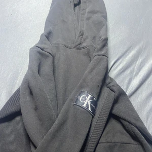 Svart hoodie från Calvin Klein Jeans - Säljer en stilren svart hoodie från Calvin Klein Jeans. Den har en klassisk design med huva och ribbade ärmslut.