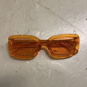 Orange solglasögon från & Other Stories - Rektangulära orangea solglasögon från & Other Stories. Transparenta bågar och matchande glas.