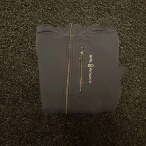 Mörkblå huvtröja från Sail Racing - Säljer en mörkblå huvtröja från Sail Racing med dragkedja framtill. Tröjan har en praktisk huva och långa ärmar. Perfekt för en avslappnad stil. 🤩👍