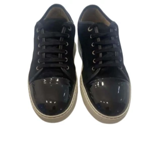 Lanvin dbb1 - Snygga svarta sneakers från Lanvin med glansig tå och snörning. Skorna har en vit sula och är tillverkade i skinn och mocka. Perfekta för en stilren look. Skriv om ni har några frågor 🍾❤️