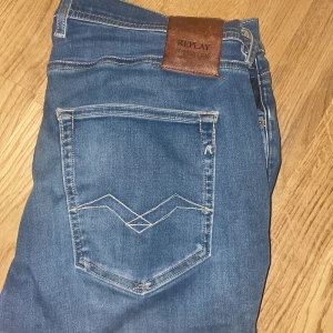 Blå jeans från Replay - Snygga blå jeans från Replay med klassisk femficksdesign och en läderpatch med logga på baksidan. Jeansen har en modern passform och är tillverkade i ett stretchigt material för extra komfort.