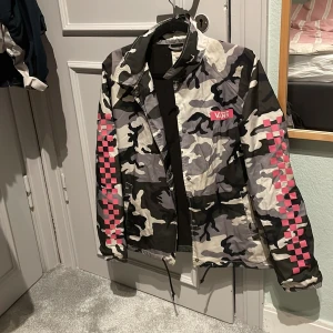 Camouflagejacka från Vans - Snygg camouflagejacka från Vans med rosa rutiga detaljer på ärmarna. 