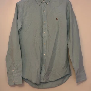 Skjorta från Polo Ralph Lauren - Turkos/ ljusblå skjorta från Ralph Lauren. Har en svag fläck på framsidan (se bild), annars i bra skick.