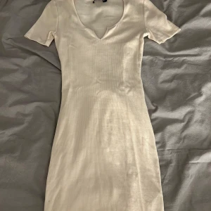 Beige ribbad klänning från Bik Bok - Säljer en stilren beige ribbad klänning från Bik Bok i storlek S. Klänningen har en v-ringad hals och korta ärmar, perfekt för en enkel och chic look. Passar bra till både vardag och speciella tillfällen. 🌟Använd 1gång💞