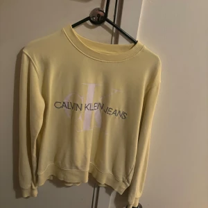 Gul sweatshirt från Calvin Klein Jeans - Säljer en snygg gul sweatshirt från Calvin Klein Jeans i storlek S. Tröjan har en klassisk rund hals och långa ärmar. Perfekt för en avslappnad stil och passar bra till både jeans och kjol. Den är i bra skick och superbekväm!