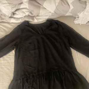 Svart långärmad klänning - Säljer en elegant svart klänning med långa ärmar och v-ringad hals. Perfekt för höst och vinter, den har en klassisk stil som passar både till vardags och festligare tillfällen. Materialet ser ut att vara mjukt och bekvämt. Perfekt för dig som vill ha en stilren look!