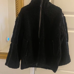NY oanvänd pilejacka / teddyjacka HM - Ny med tags. En svart tjock och varm teddyjacka i mjuk pile med kantband i ytbehandlad kvalitet. Jackan har lös passform, ståkrage, tvåvägsdragkedja fram och kängurufickor. Fodrad. Storlek: M (oversize)