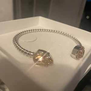 Silverarmband med kristaller från Caroline Svedbom - Snyggt och elegant armband i silver från Caroline Svedbom. Armbandet har en vriden design och är dekorerat med två stora, glittrande kristaller. Kommer i originalförpackning (armbandet är aldrig använt och helt nytt då jag fick det i present men förpackningen har en liten fläck) originalpriset är 800!  Den är mer ljusrosa i verkligheten!