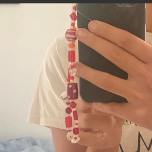 Chain till mobilen - Jättegullig "chain" till mobilen i röda och orangea pärlor!!  Egengjord. Ungefär 32 cm lång. Pärlorna är i glas och tråden elastisk❤️🧡💛