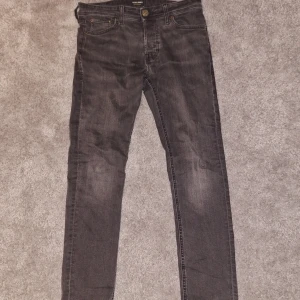 Svarta jeans från Jack & Jones - Snygga svarta jeans från Jack & Jones i modellen Slim/Glenn. De har en slim passform och är tillverkade i ett bekvämt jeansmaterial. Byxorna har klassiska fem fickor och stängs med dragkedja och knapp.