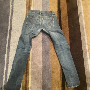 Dondup  - Säljer ett par klassiska blå jeansbyxor med en straight passform. De har en traditionell femficksdesign och en snygg tvättad look. Perfekta för en avslappnad stil.