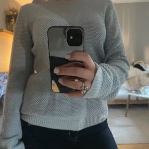 Ljusblå stickad tröja - Säljer en mysig ljusblå stickad tröja med rund hals och långa ärmar. Perfekt för kyliga dagar och enkel att matcha med olika outfits. Tröjan har en ribbad kant vid ärmslut och nederkant.