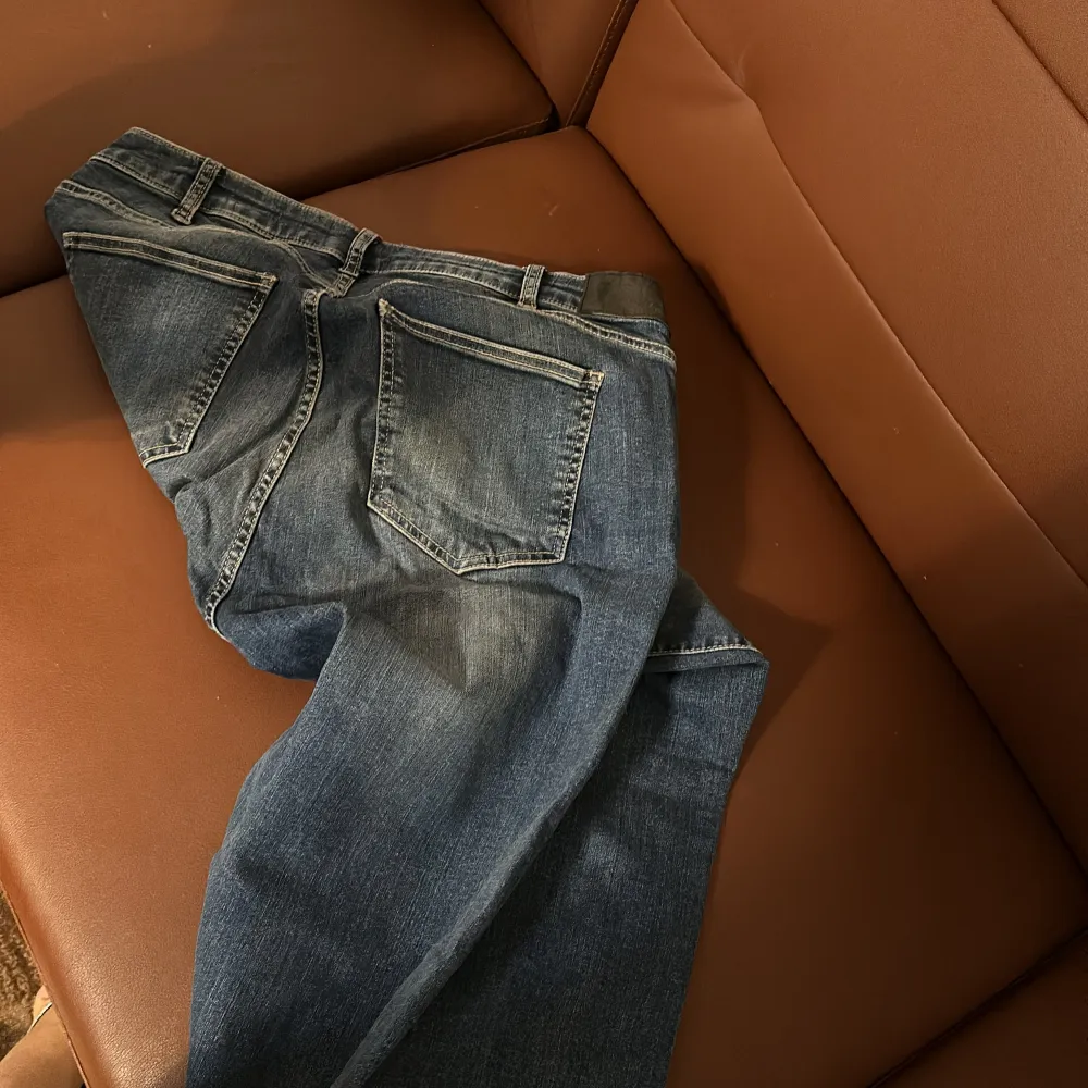 Snygga blå jeans från Dressmann med en klassisk design. De har en normal passform och är tillverkade i slitstarkt denim. Perfekta för en avslappnad stil med fem fickor och knappgylf.. Farkut & Housut.
