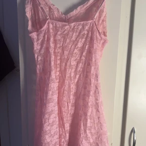 Rosa spetsklänning - Söt rosa klänning i spets med smala axelband och v-ringad design. Perfekt för en romantisk look med sin blommiga spets och lätta material.