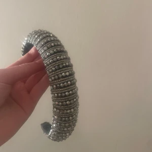 Glittrigt diadem med pärlor - Snyggt diadem i silver med glittriga detaljer och pärlor. Perfekt för att ge en extra touch till din outfit. Diademet har en elegant design som passar bra till festliga tillfällen.