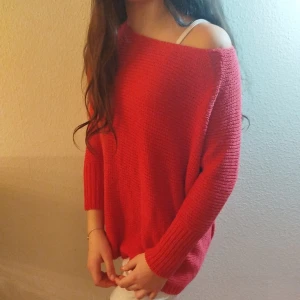 Röd stickad tröja från Vero Moda - Säljer en snygg röd stickad tröja från Vero Moda. Tröjan har en offshoulder-design och knappar på baksidan. Perfekt för en avslappnad stil.