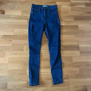 Blå skinny jeans - Snygga blå jeansbyxor med hög midja. Byxorna har en knapp och dragkedja framtill. Perfekta för en avslappnad stil.