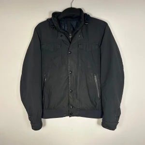 Massimo Dutti Jacka - Snygg svart jacka från Massimo Dutti med huva och dragkedja. Jackan har knappar och flera praktiska fickor. Perfekt för kyligare dagar. Det finns några skavanker på ärmarna men inget som tänkas på vid användning. Skriv vid ytterligare frågor eller funderingar🤝