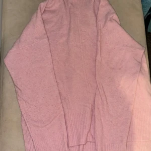 Rosa stickad tröja från Esprit - Mysig rosa stickad tröja från Esprit. Perfekt för kyliga dagar med sin mjuka och bekväma passform. Tröjan har långa ärmar och ribbade detaljer vid ärmslut och nederkant.