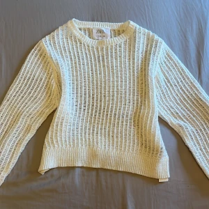 Vit stickad tröja från Zara - Säljer en vit stickad tröja från Zara med ett unikt öppet stickmönster. Tröjan har långa ärmar och ribbade kanter vid ärmslut och nederkant. I stl 11-12 men passar xs och s💗