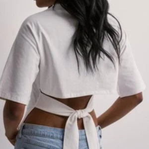 Vit croppad topp med knyt - Snygg vit croppad topp med knyt i ryggen från nelly i storlek xs. 