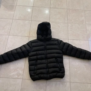 Svart boys down jkt-kille - Denna jacka passar på 14 åringar eller barn som är 166cm långa. Jackan har ett jätte litet hål på vänstra fickan som vi sytt igen. Sen har den ett annat jätte litet hål under högra armen som knappt är synligt. Nypris ca 4500kr