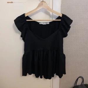 Svart blus med volangdetaljer - Snygg svart blus från lager 157 med volangdetaljer och v-ringad design. Aldrig använt, men klippt bort prislappen.🖤